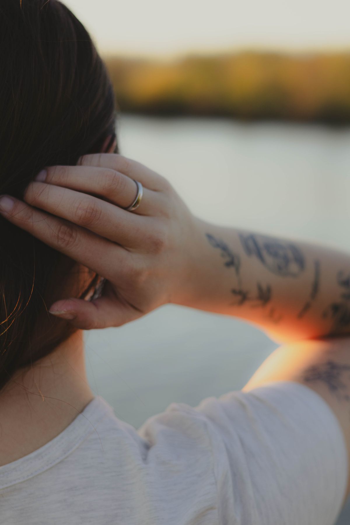 Détail d'une main tatouée devant le soleil couchant