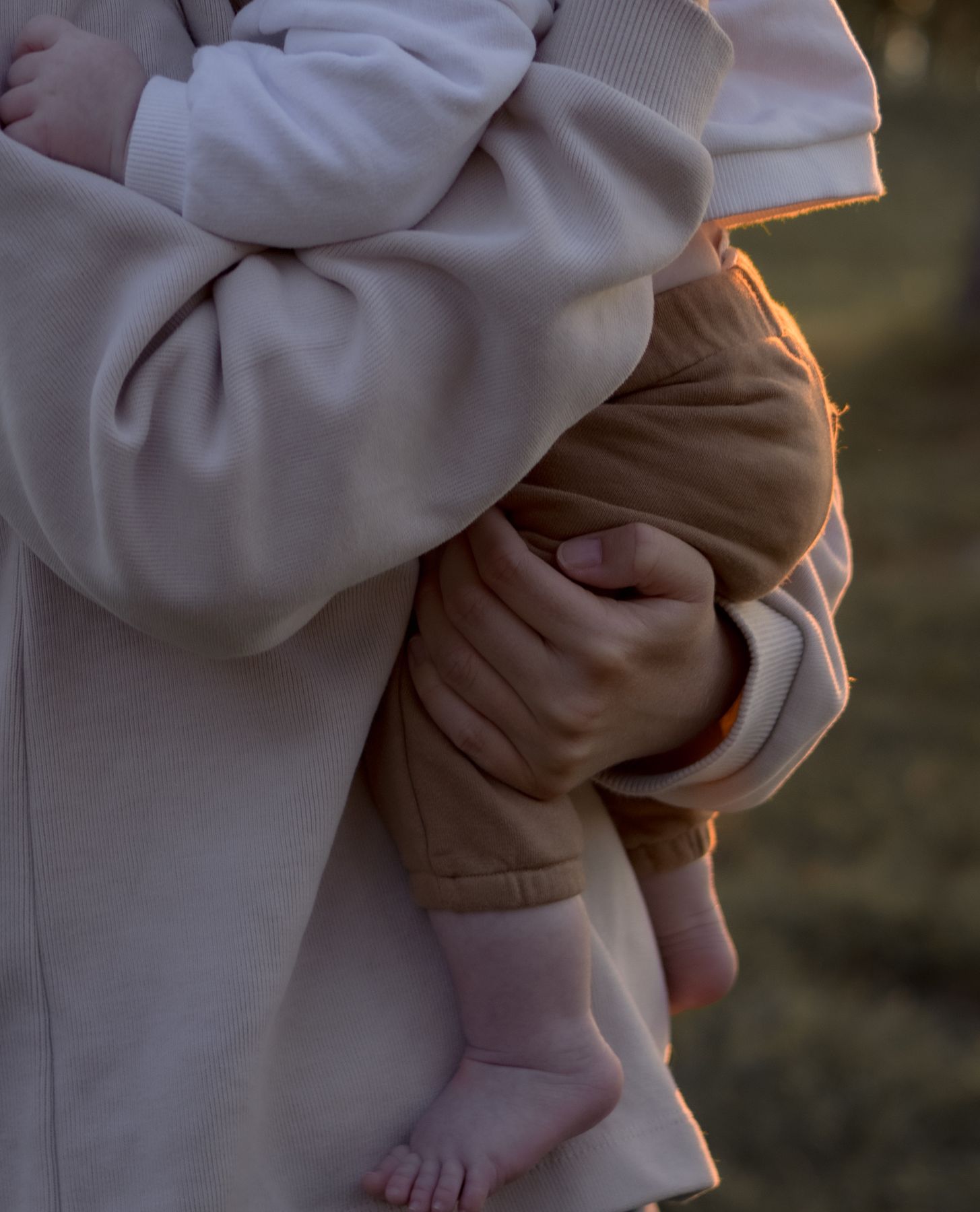 Petits pieds de bébé blotti dans les bras d'un parent, lumière dorée