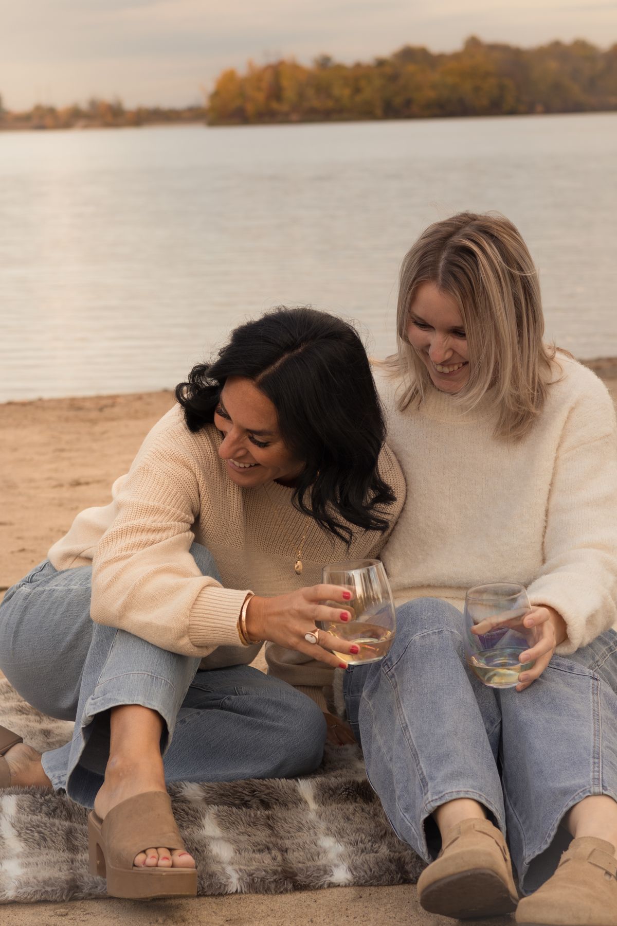 Deux amies riant ensemble sur une plage d'automne