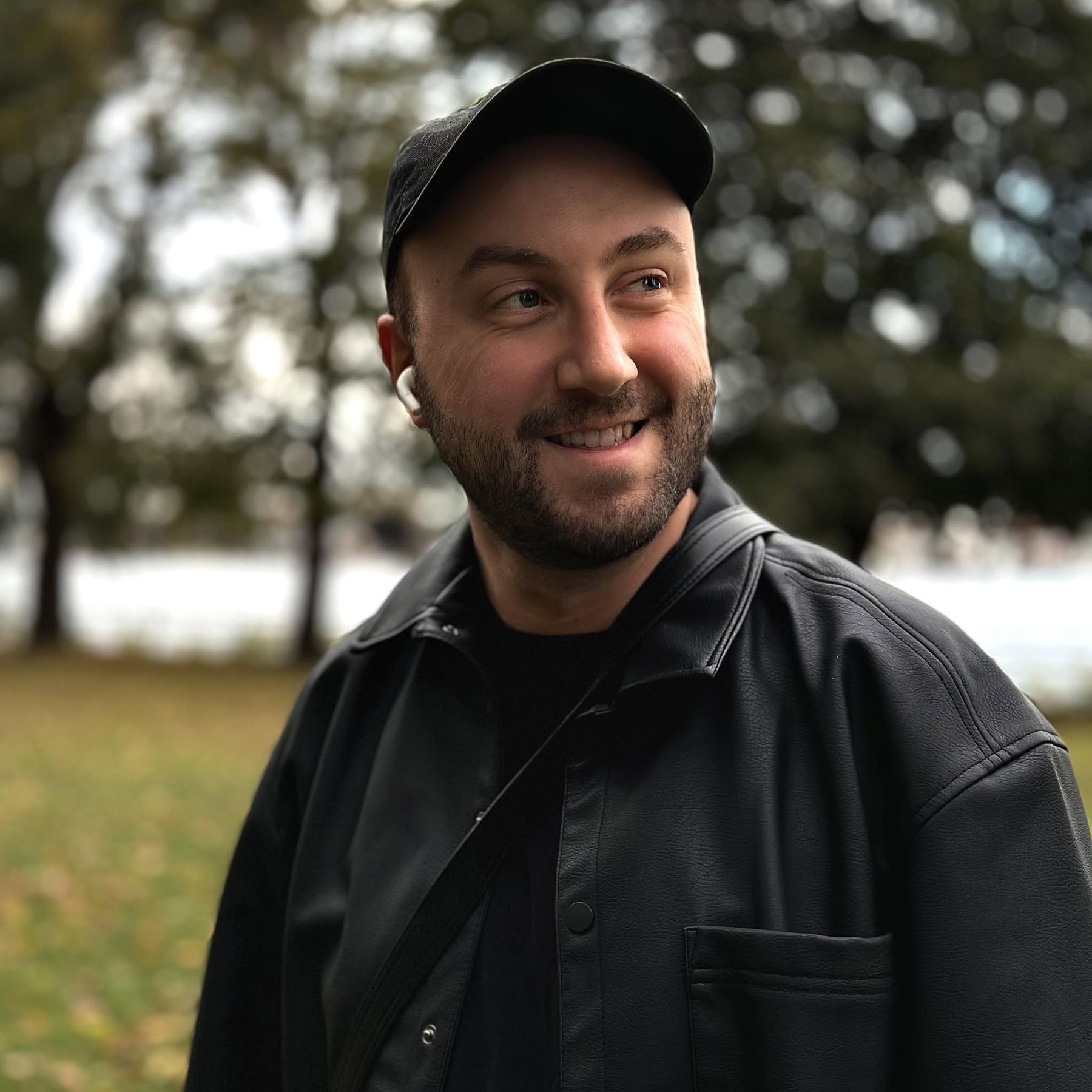 Mathieu Carrière, photographe, souriant en veste noire au bord de l'eau